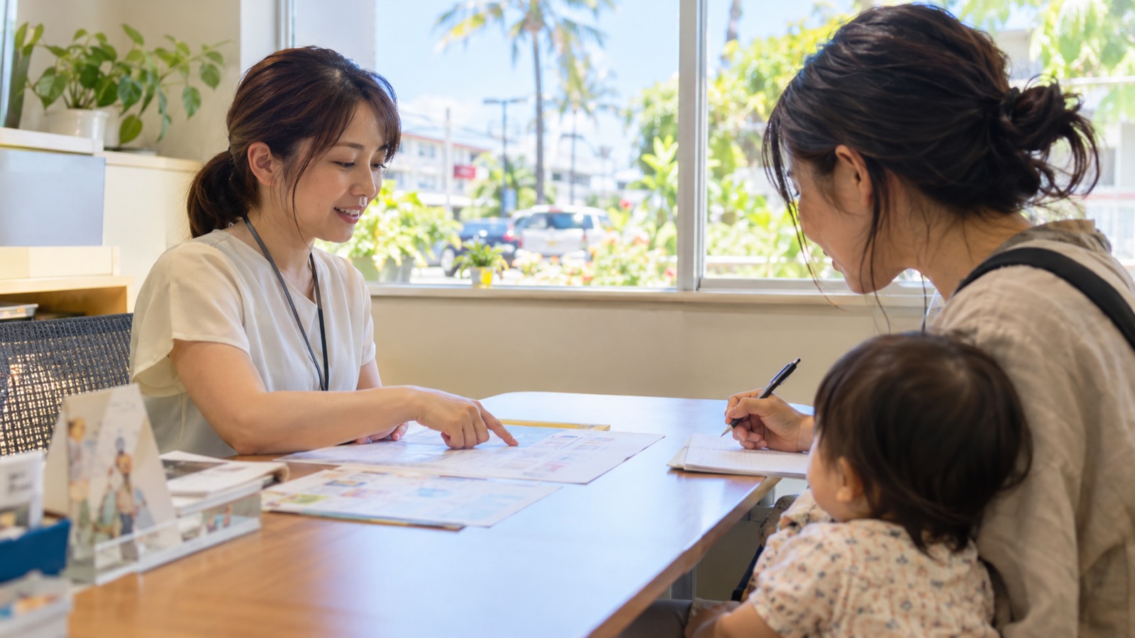 日本語スタッフが保護者に日程表を見せながら説明する手元と横顔